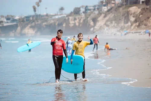 A surf instructor and a surf student walking on the shoreline in San Diego after a private surf lesson.