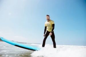 A private surf lesson customer riding a wave in a yellow jersey.