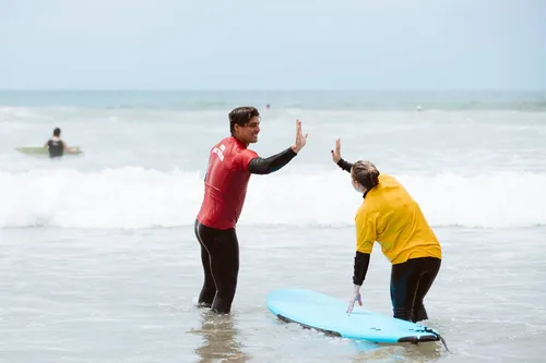 A San Diego Surf School instructor giving a high five in the shoreline to a customer during a private surf lesson in San Diego.