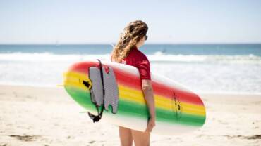 surfing techniques woman walking surfboard on the beach into the ocean