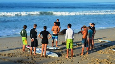 group of people standing on the beach with different things to wear for surfing