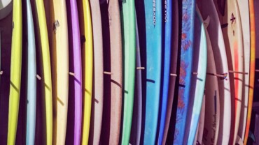 different colors and types of surfboards on a rack vertically