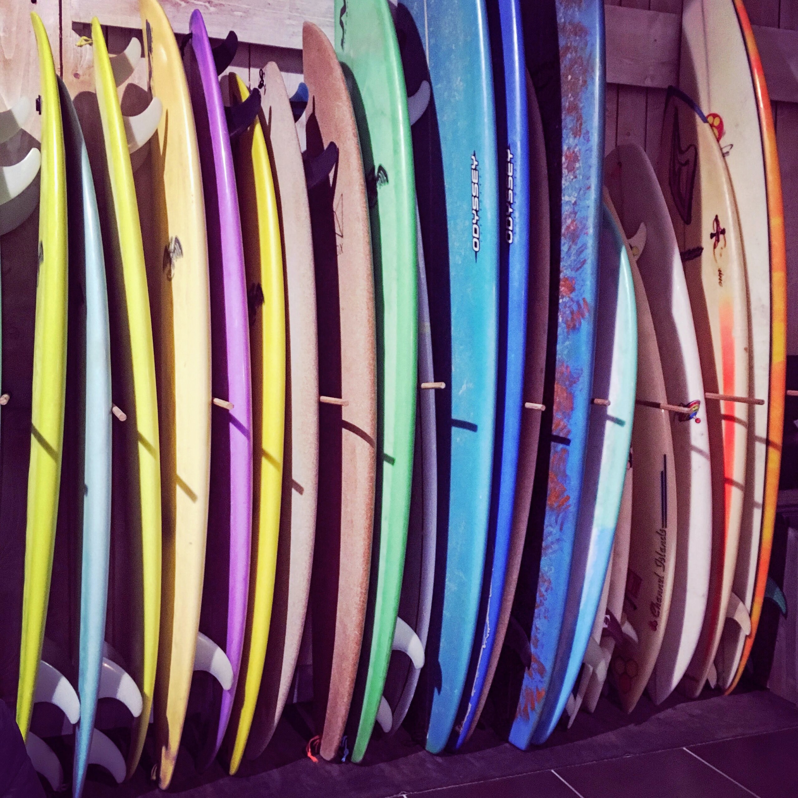 different colors and types of surfboards on a rack vertically