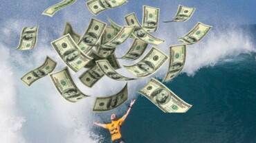 man surfing in breaking wave with dollar bills flying in the air cost of surfing