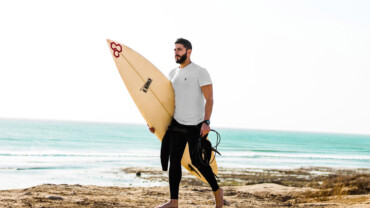 man holding surfboard on beach get started with surfing