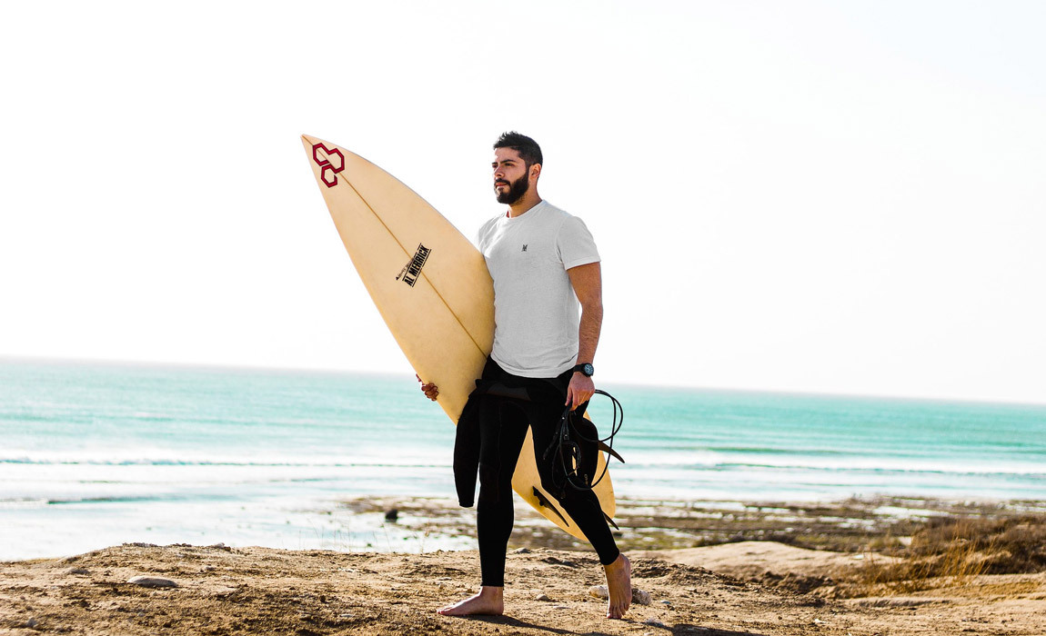 man holding surfboard on beach get started with surfing